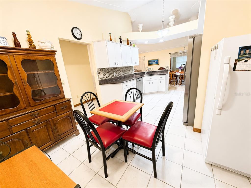 A kitchen and dining area feature white cabinets, tile flooring, and a small square table — 13506 SW 43RD CIRCLE SW, OCALA, FL