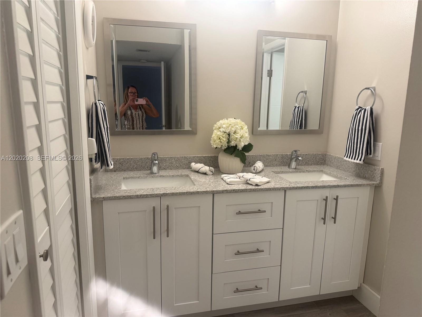 A double-sink bathroom vanity features white cabinets, a granite countertop, and two framed mirrors — 436 Lakeview Dr # 203, Weston FL 33326, WESTON, FL