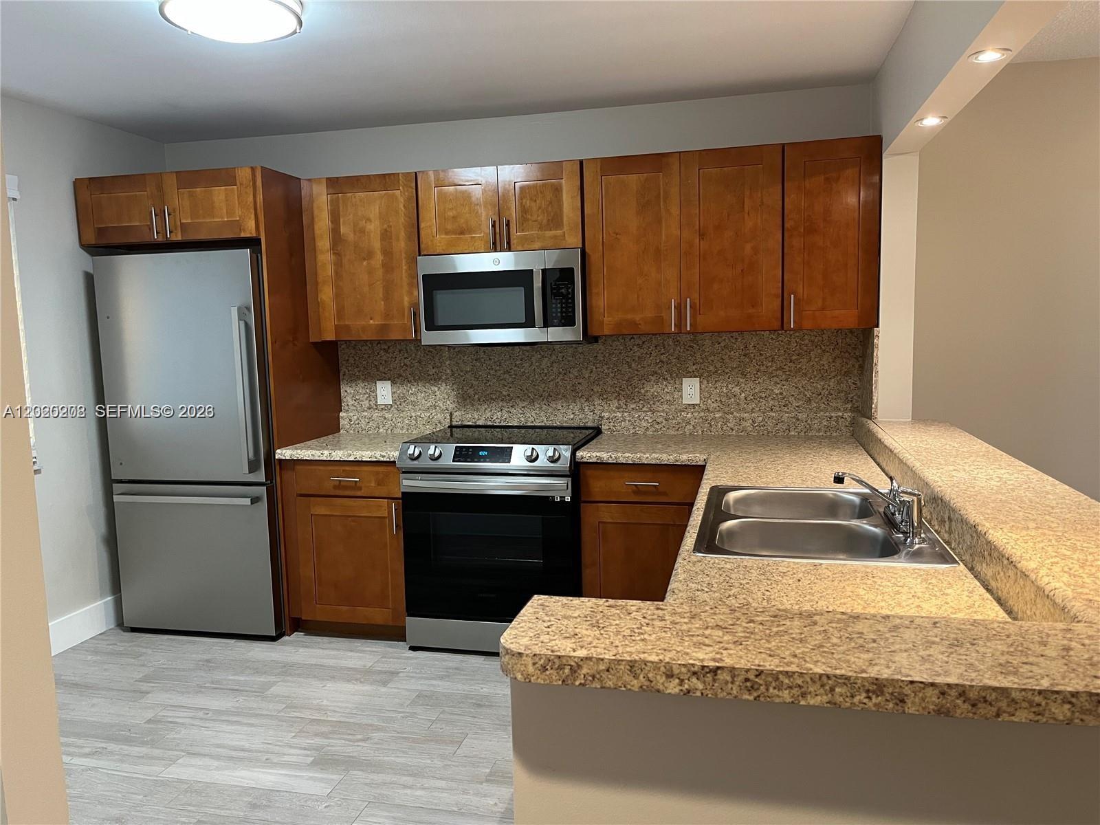A kitchen features wood cabinets, stainless steel appliances, and speckled granite countertops — 436 Lakeview Dr # 203, Weston FL 33326, WESTON, FL