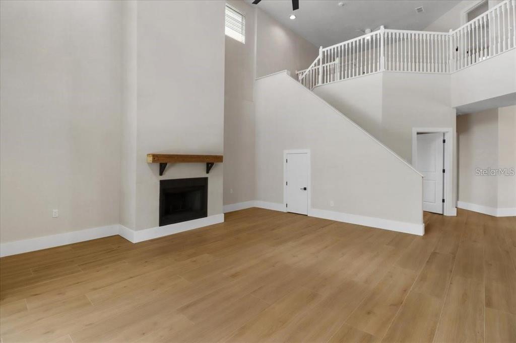 A living room features light wood flooring, a fireplace with a wooden mantel, and stairs — 14024 CHERRY BUSH COURT, ORLANDO, FL