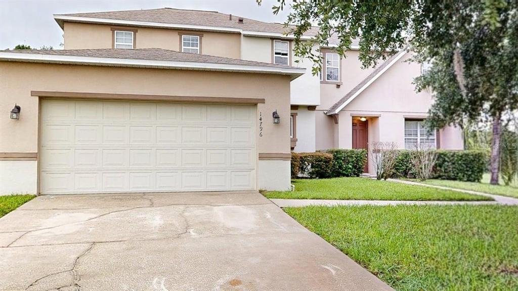 A two-story house features a tan stucco exterior, a two-car garage, and a front lawn — 14796 TULLAMORE LOOP, WINTER GARDEN, FL