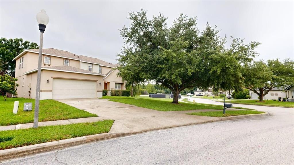 A two-story suburban house with a beige exterior, a two-car garage, and a large tree — 14796 TULLAMORE LOOP, WINTER GARDEN, FL
