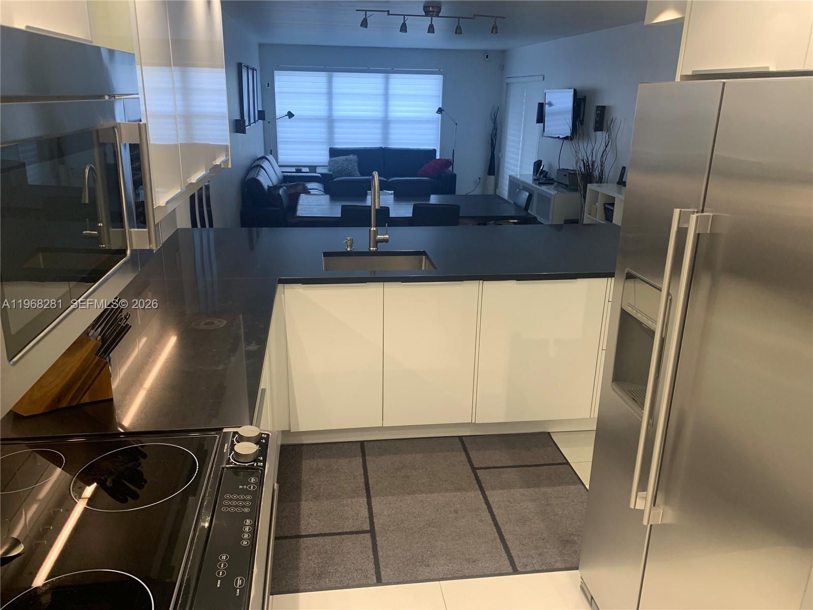 A modern kitchen features white cabinets, black countertops, and stainless steel appliances — 2326 S Cypress Bend Dr # 221, Pompano Beach FL 33069, POMPANO BEACH, FL
