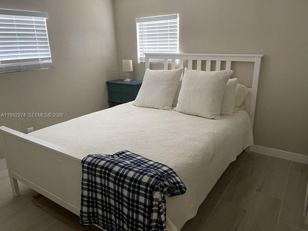 A bedroom features a white bed frame, white bedding, a plaid throw, and a blue nightstand — 721 Garden State Ln, Key Largo FL 33037, KEY LARGO, FL