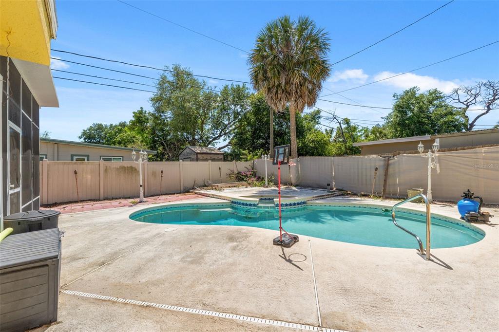A backyard features a swimming pool with a spa, a basketball hoop, and a privacy fence — 7300 11TH AVENUE N, ST PETERSBURG, FL