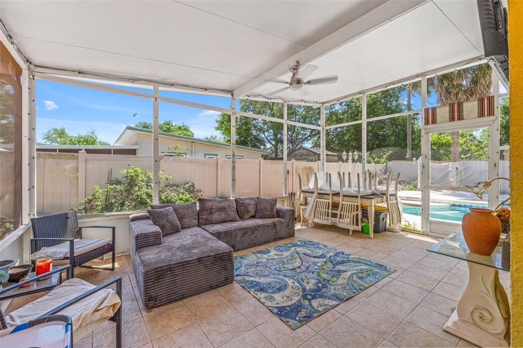 A screened-in patio features tile flooring, a sectional sofa, a dining set, and a pool — 7300 11TH AVENUE N, ST PETERSBURG, FL
