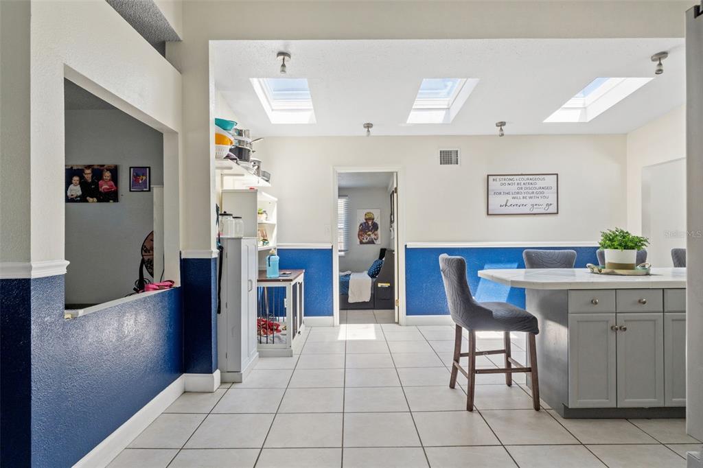 A kitchen with a center island, blue wainscoting, tile flooring, and three skylights — 7300 11TH AVENUE N, ST PETERSBURG, FL