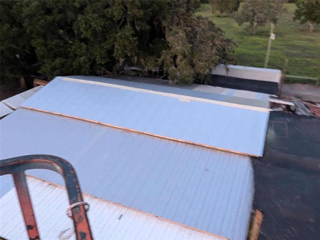 An elevated view shows the metal roof of a building with a large tree nearby — 8780 E DERBY OAKS DRIVE, FLORAL CITY, FL