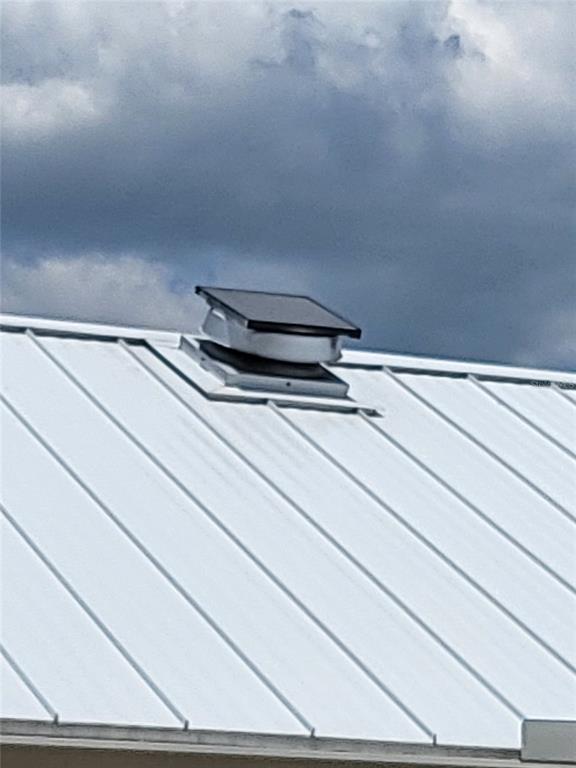A solar-powered attic ventilation fan is mounted on a white standing-seam metal roof — 8780 E DERBY OAKS DRIVE, FLORAL CITY, FL