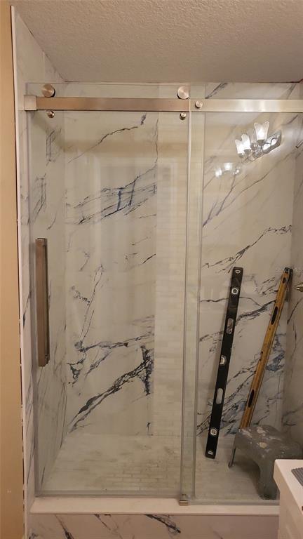A walk-in shower features a sliding glass door and white marble-patterned tile walls — 8780 E DERBY OAKS DRIVE, FLORAL CITY, FL