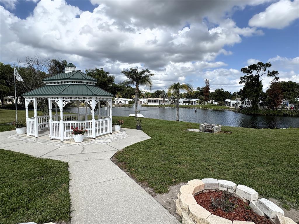 A white gazebo sits on a concrete path near a pond in a residential community — 446 CITRUS RIDGE, DAVENPORT, FL