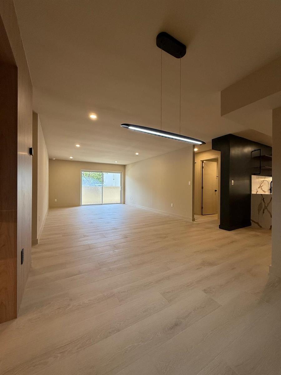 An open-concept living area features light wood-look flooring, recessed lighting, and a modern pendant light — 7715 SW 86th Street # 111, Miami FL 33143, MIAMI, FL