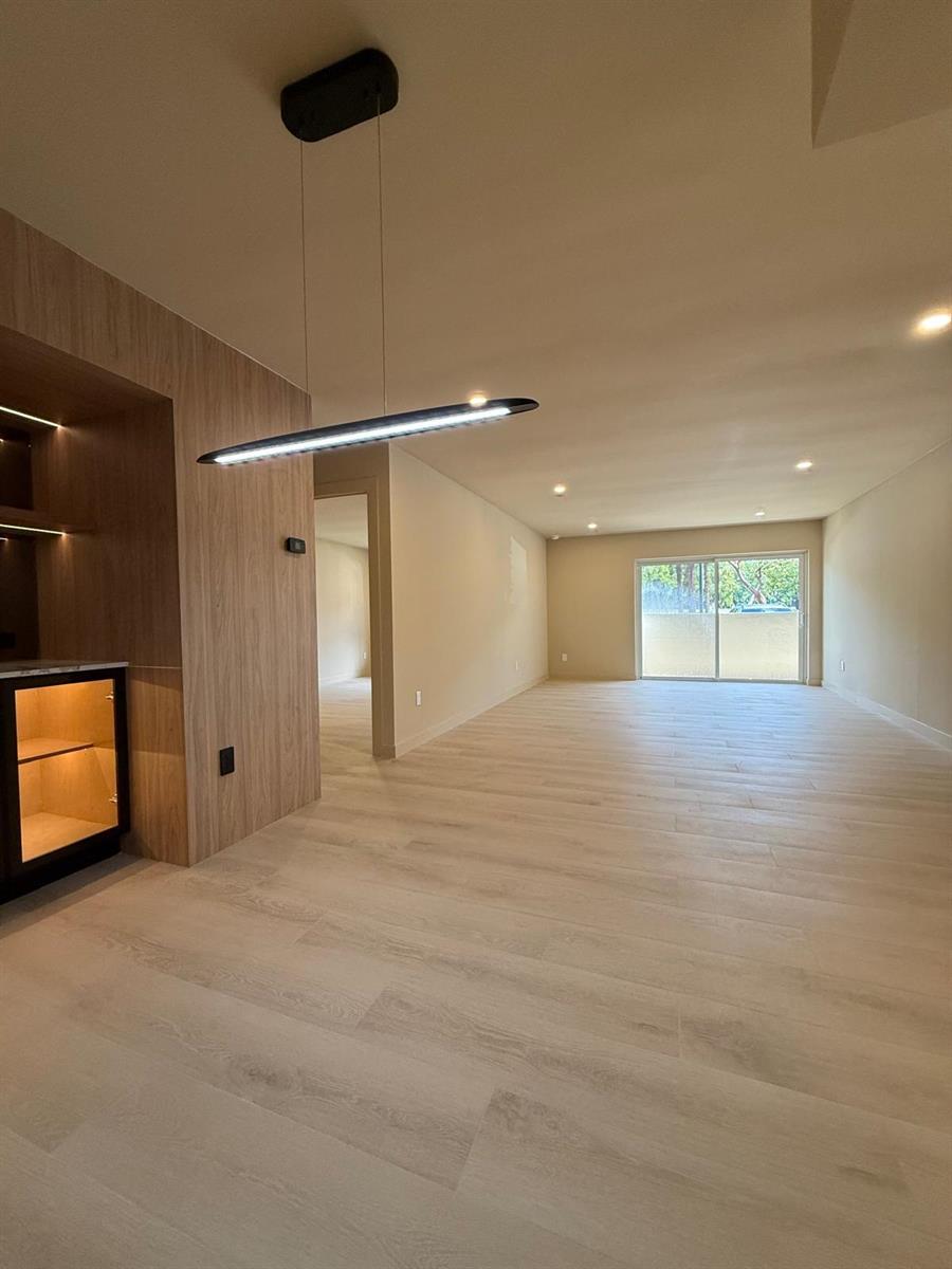 A modern living area features light wood-look flooring, a linear pendant light, and wood paneling — 7715 SW 86th Street # 111, Miami FL 33143, MIAMI, FL