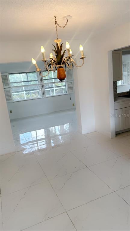 A dining area features white marble-look tile flooring and a pineapple-themed chandelier — 9102 NW 81ST COURT, TAMARAC, FL