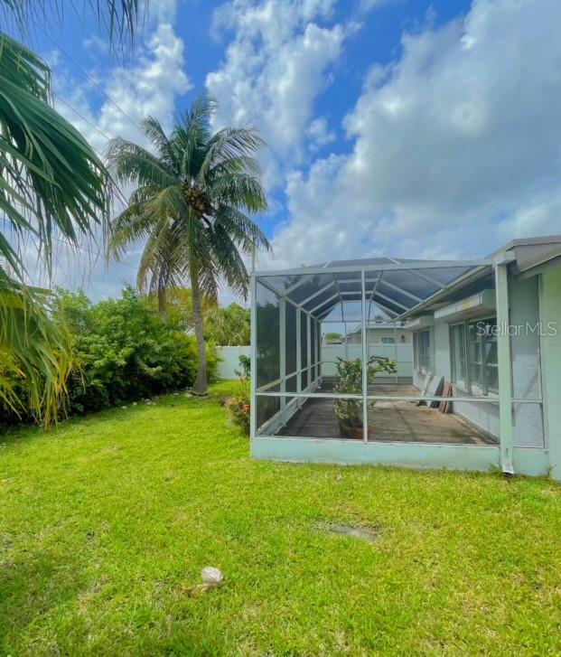 A backyard view shows a screened-in patio attached to a house next to a palm tree — 9102 NW 81ST COURT, TAMARAC, FL