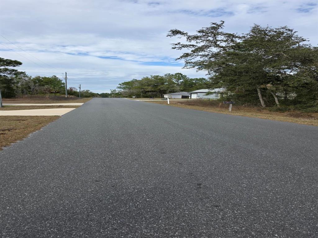 A paved residential street stretches forward with trees and houses visible in the distance — SW 140TH COURT, OCALA, FL