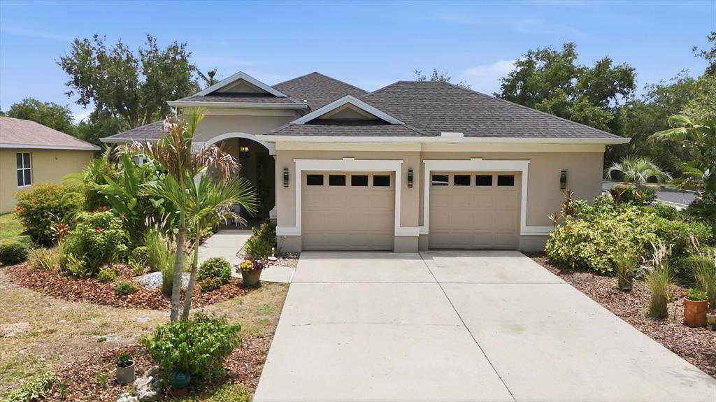 A single-story house with a two-car garage and landscaped front yard under a blue sky — 428 SNAPDRAGON LOOP, BRADENTON, FL