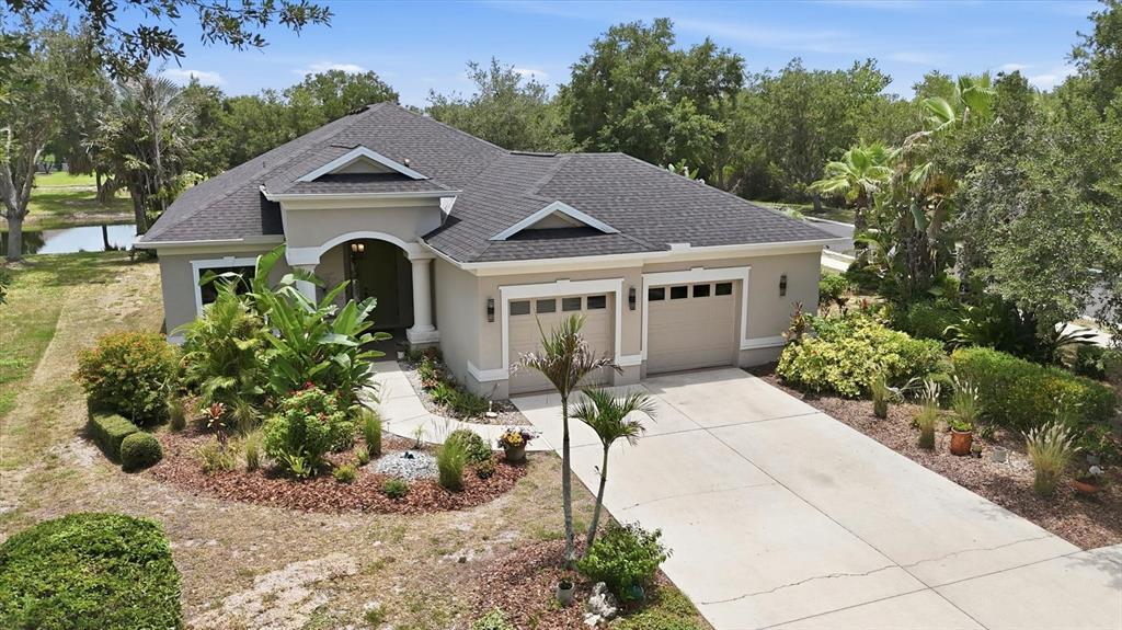 An aerial view shows a single-story house with a gray roof, beige stucco, and two-car garage — 428 SNAPDRAGON LOOP, BRADENTON, FL