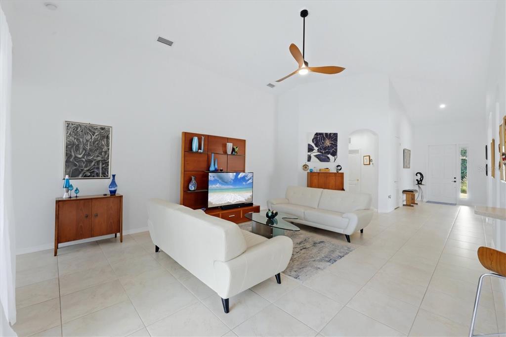 A bright living room features white sofas, a wooden media unit, and a ceiling fan — 428 SNAPDRAGON LOOP, BRADENTON, FL
