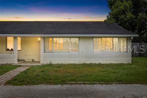 The exterior of a single-story house features a light-colored facade, a dark roof, and windows — 2196 BELL CHEER DRIVE, CLEARWATER, FL
