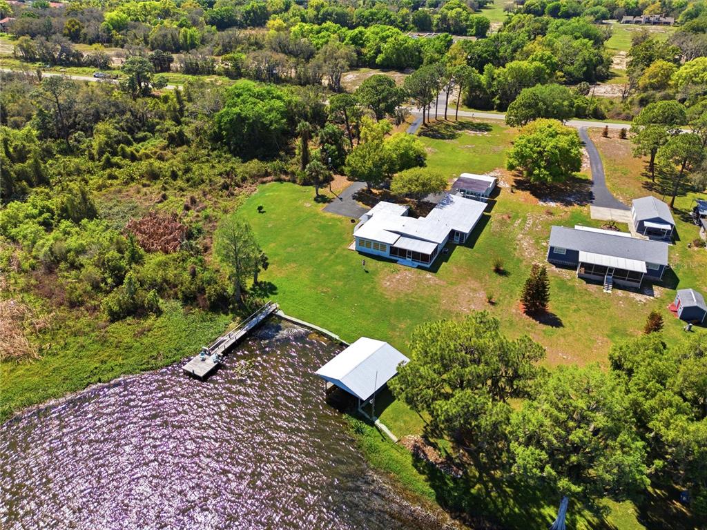 A living room with tile floors, two ceiling fans, and large windows overlooking a lake — 8342 W LAKE MARION ROAD, HAINES CITY, FL