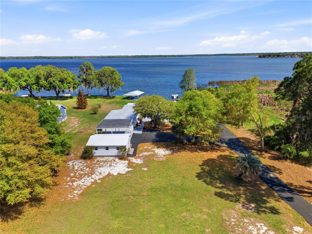 A kitchen features wood cabinets, stainless steel appliances, granite countertops, and light-colored tile flooring — 8342 W LAKE MARION ROAD, HAINES CITY, FL