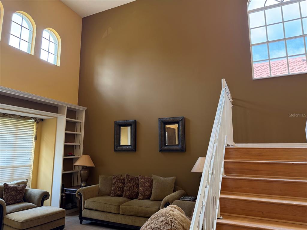 A living room with high ceilings, a staircase, two windows, and a built-in bookshelf — 18826 AVENUE BIARRITZ, LUTZ, FL