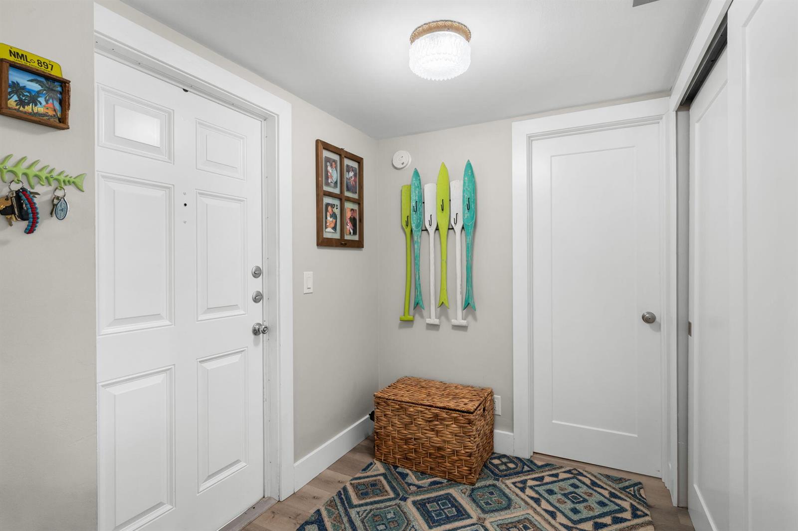 An entryway features a white door, a wicker storage chest, and decorative oar wall hooks — 3412 NE Causeway Boulevard # 102, Jensen Beach FL 34957, JENSEN BEACH, FL
