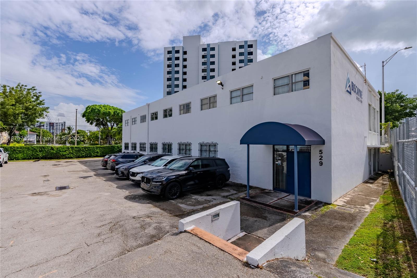 A white two-story commercial building features a blue awning over the entrance and a parking lot — 529 W Flagler St, Miami FL 33130, MIAMI, FL