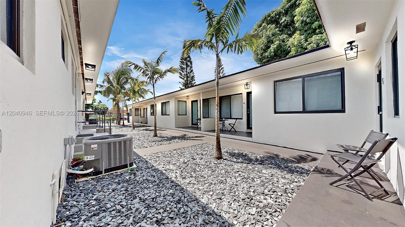 A row of white apartment units features a gravel courtyard with palm trees — 101 W 11th St # 4, Hialeah FL 33010, HIALEAH, FL