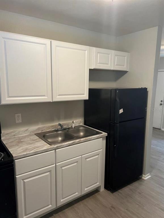 A kitchen features white cabinets, a double-basin sink, marble-patterned countertops, and a black refrigerator — 8123 N ALASKA STREET UNIT A, TAMPA, FL