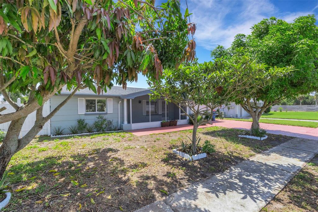 A single-story house with a screened porch, gray siding, and trees in the front yard — 1240 TRUNKFISH DRIVE, HOLIDAY, FL