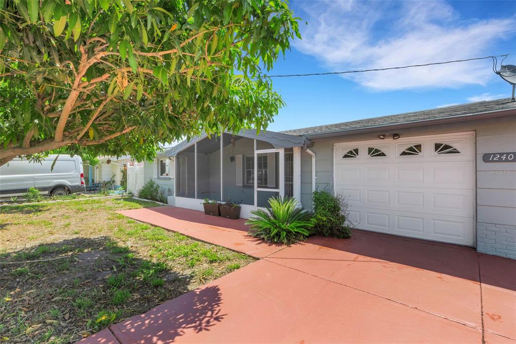 A single-story house with a screened-in front porch, a white garage door, and a tree — 1240 TRUNKFISH DRIVE, HOLIDAY, FL