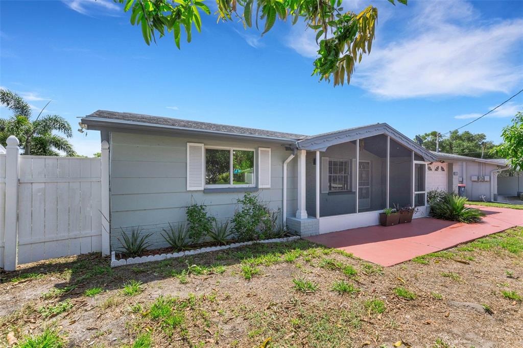 A single-story house with gray siding, a screened-in porch, and a white vinyl fence — 1240 TRUNKFISH DRIVE, HOLIDAY, FL