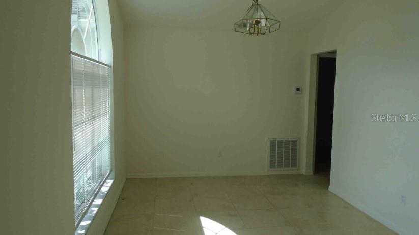 An empty dining room features tile flooring, a large arched window, and a hanging light fixture — 3142 ATWATER DRIVE, ORLANDO, FL