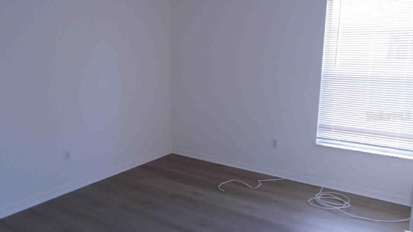 An empty room with white walls, wood-look flooring, and a window with closed blinds — 3142 ATWATER DRIVE, ORLANDO, FL