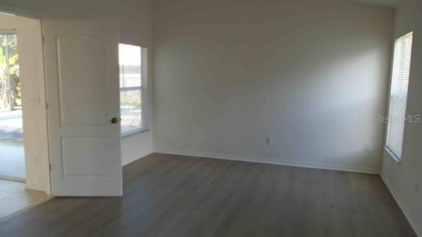 An empty room with light wood-look flooring, white walls, two windows, and an open door — 3142 ATWATER DRIVE, ORLANDO, FL