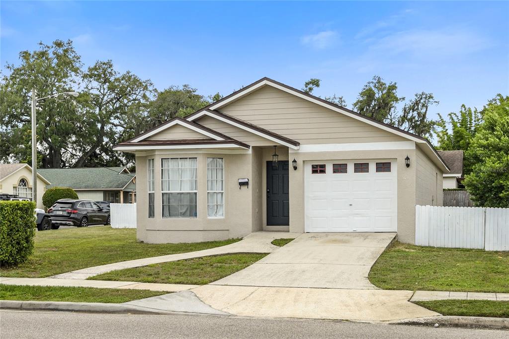 A single-story house with a beige exterior, a front-facing garage, and a bay window — 301 S CAPEN AVE, WINTER PARK, FL