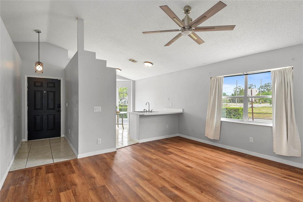 A living room with wood-look flooring, a ceiling fan, and an adjacent kitchen area — 301 S CAPEN AVE, WINTER PARK, FL