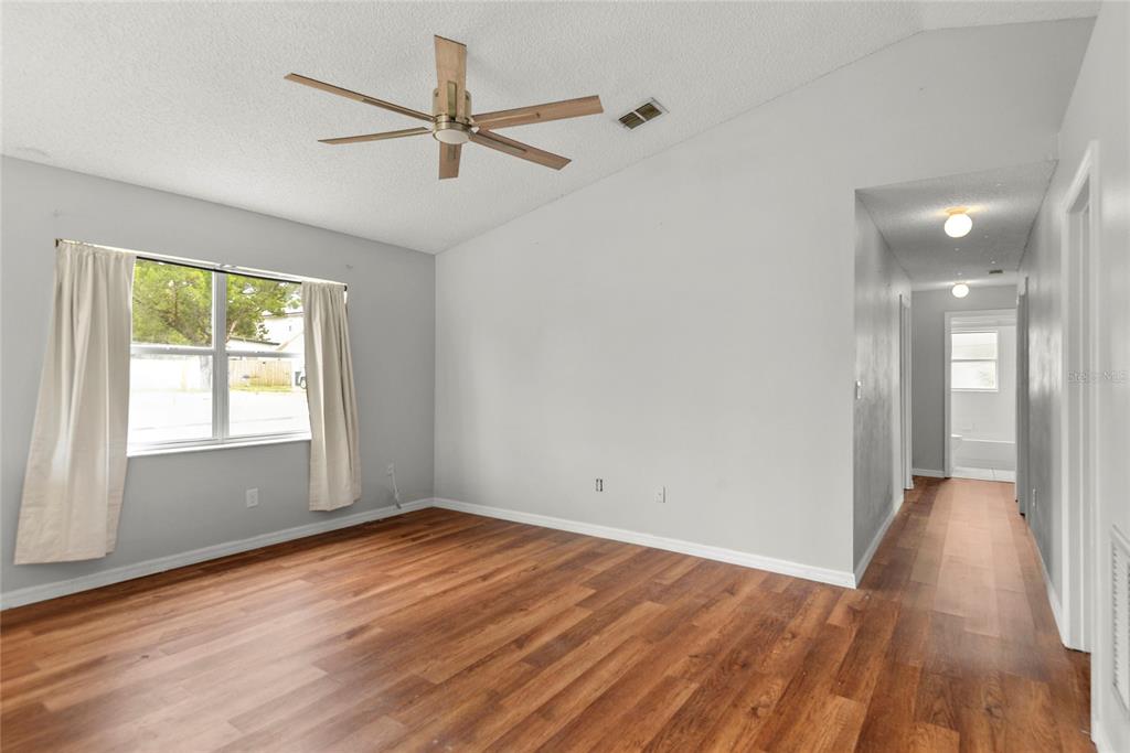 An empty room with wood-look flooring, a ceiling fan, and a hallway leading to a bathroom — 301 S CAPEN AVE, WINTER PARK, FL