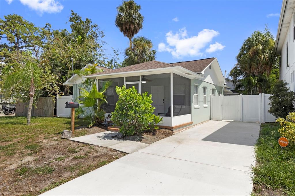 A light green house with a screened-in front porch and a concrete driveway — 1906 W GRAY STREET, TAMPA, FL