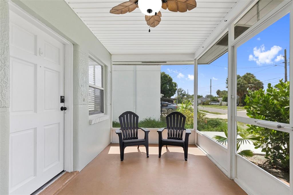 A screened-in porch features a ceiling fan, two black chairs, and a white entry door — 1906 W GRAY STREET, TAMPA, FL