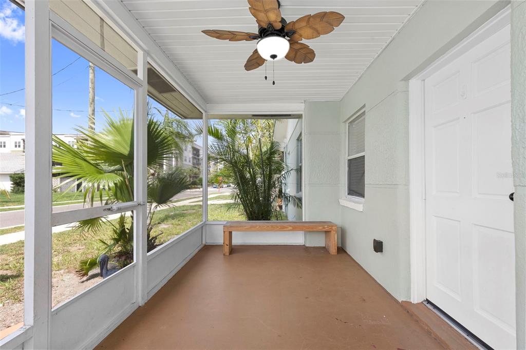 A screened-in porch features a wooden bench, a ceiling fan, and a white entry door — 1906 W GRAY STREET, TAMPA, FL