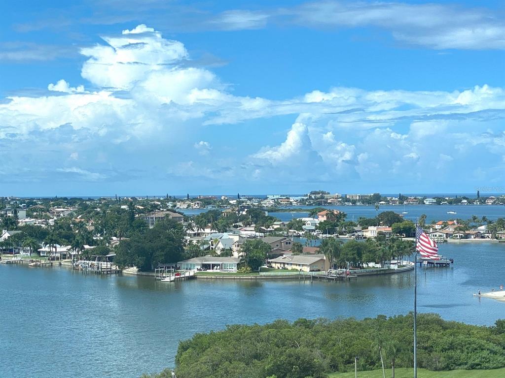 A high-angle view of a coastal neighborhood with houses, docks, and an American flag — 100 BLUFF VIEW DRIVE UNIT 317A, BELLEAIR BLUFFS, FL