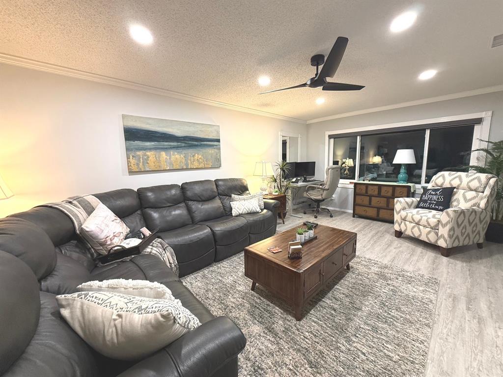 A living room features a dark leather sectional, wooden coffee table, and patterned armchair — 100 BLUFF VIEW DRIVE UNIT 317A, BELLEAIR BLUFFS, FL
