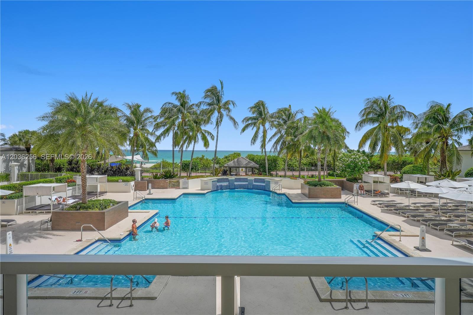 An outdoor swimming pool with palm trees and a view of the ocean — 4779 Collins Ave # 506, Miami Beach FL 33140, MIAMI BEACH, FL