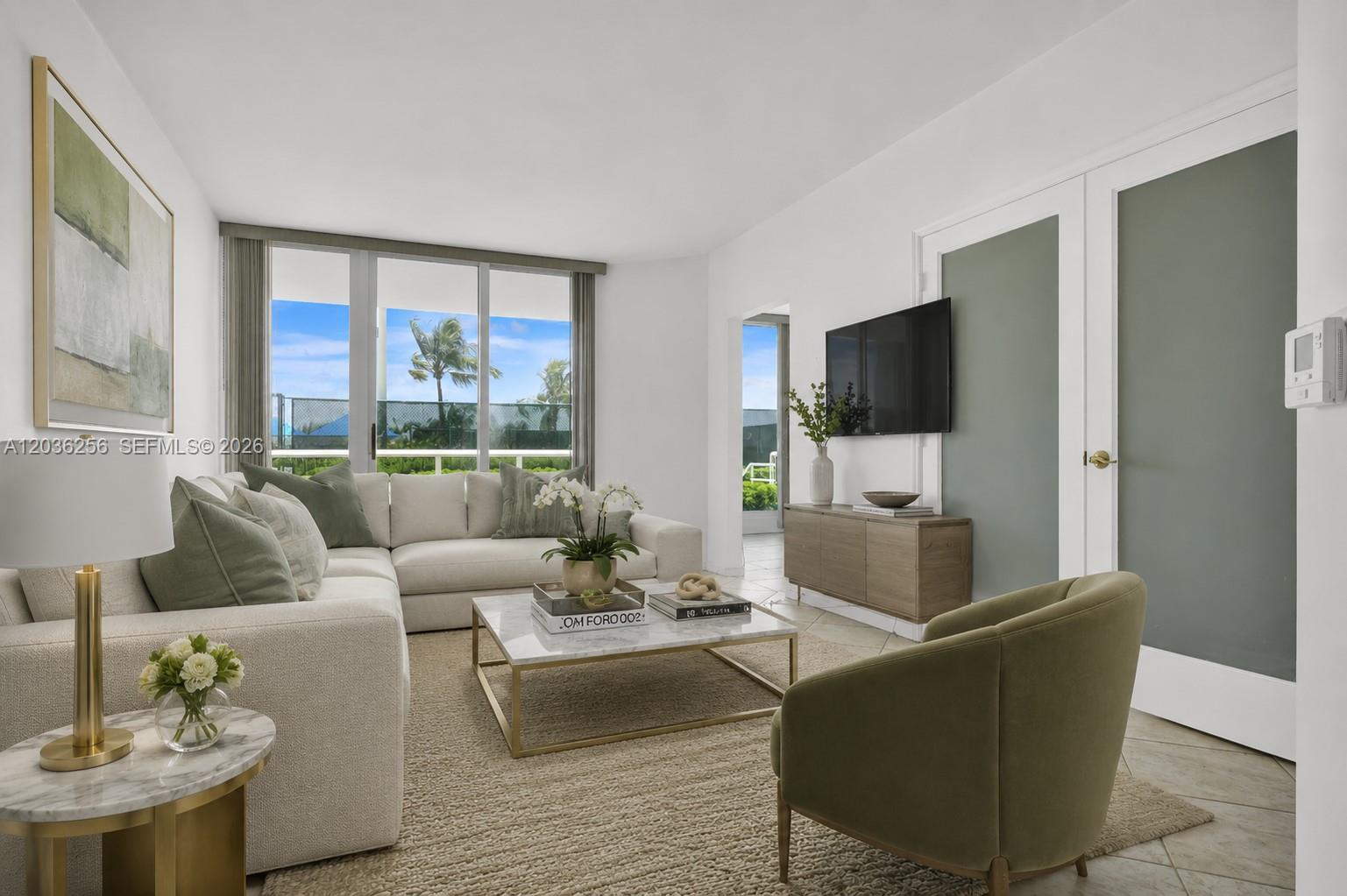 A living room features a sectional sofa, a coffee table, and a wall-mounted television — 4779 Collins Ave # 506, Miami Beach FL 33140, MIAMI BEACH, FL