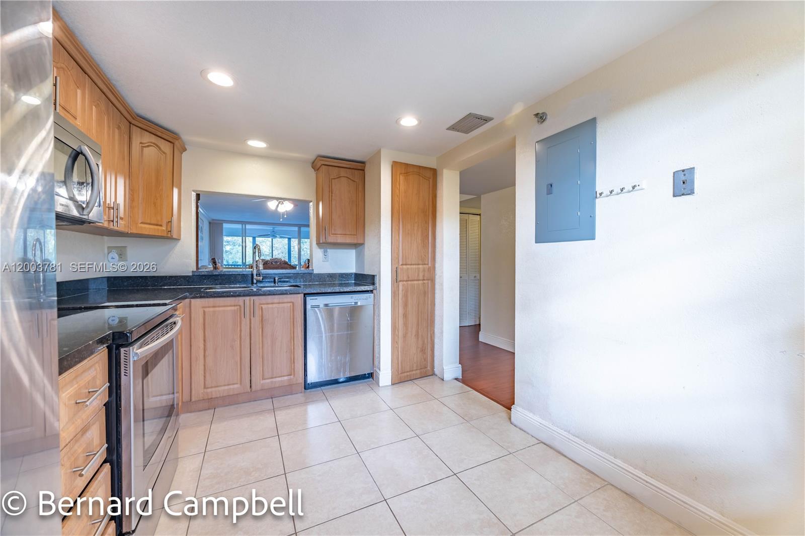 This kitchen features light wood cabinets, dark countertops, stainless steel appliances, and tile flooring — 3940 Inverrary Blvd # A, Lauderhill FL 33319, LAUDERHILL, FL