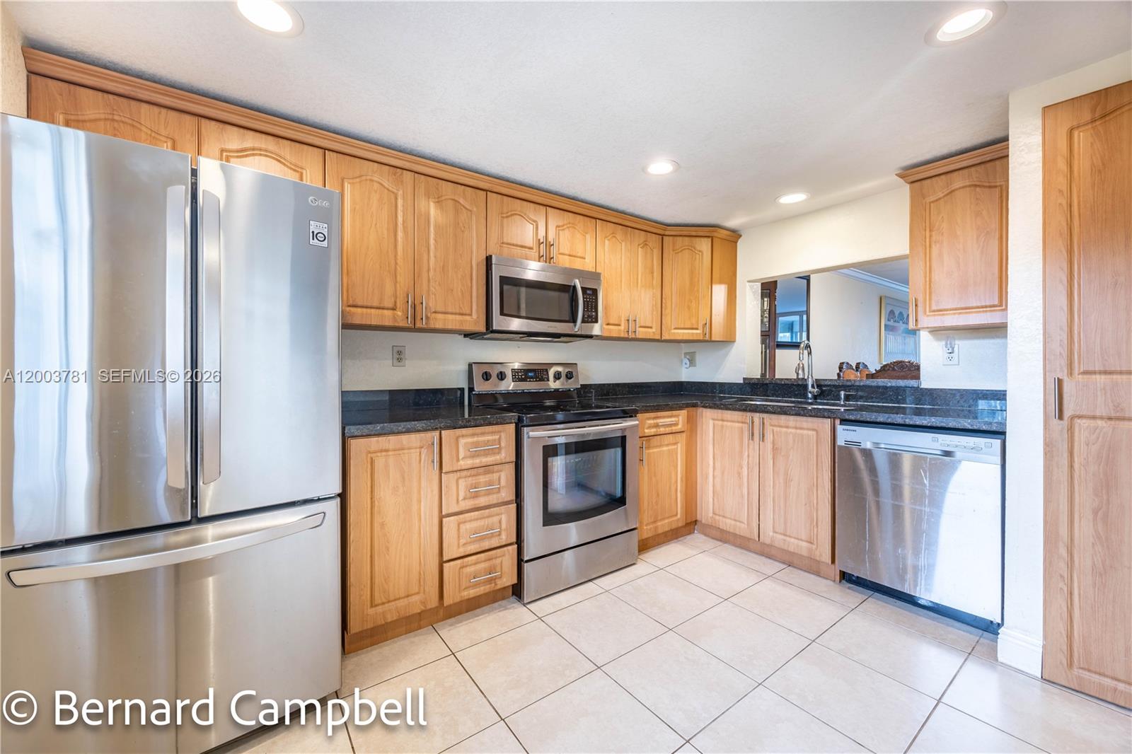 A kitchen features light wood cabinets, stainless steel appliances, and dark granite countertops — 3940 Inverrary Blvd # A, Lauderhill FL 33319, LAUDERHILL, FL