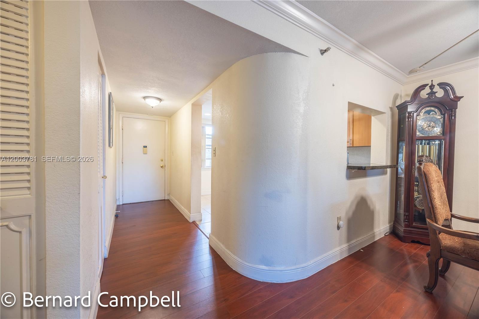 A hallway with wood flooring leads to an entrance door beside a curved wall — 3940 Inverrary Blvd # A, Lauderhill FL 33319, LAUDERHILL, FL